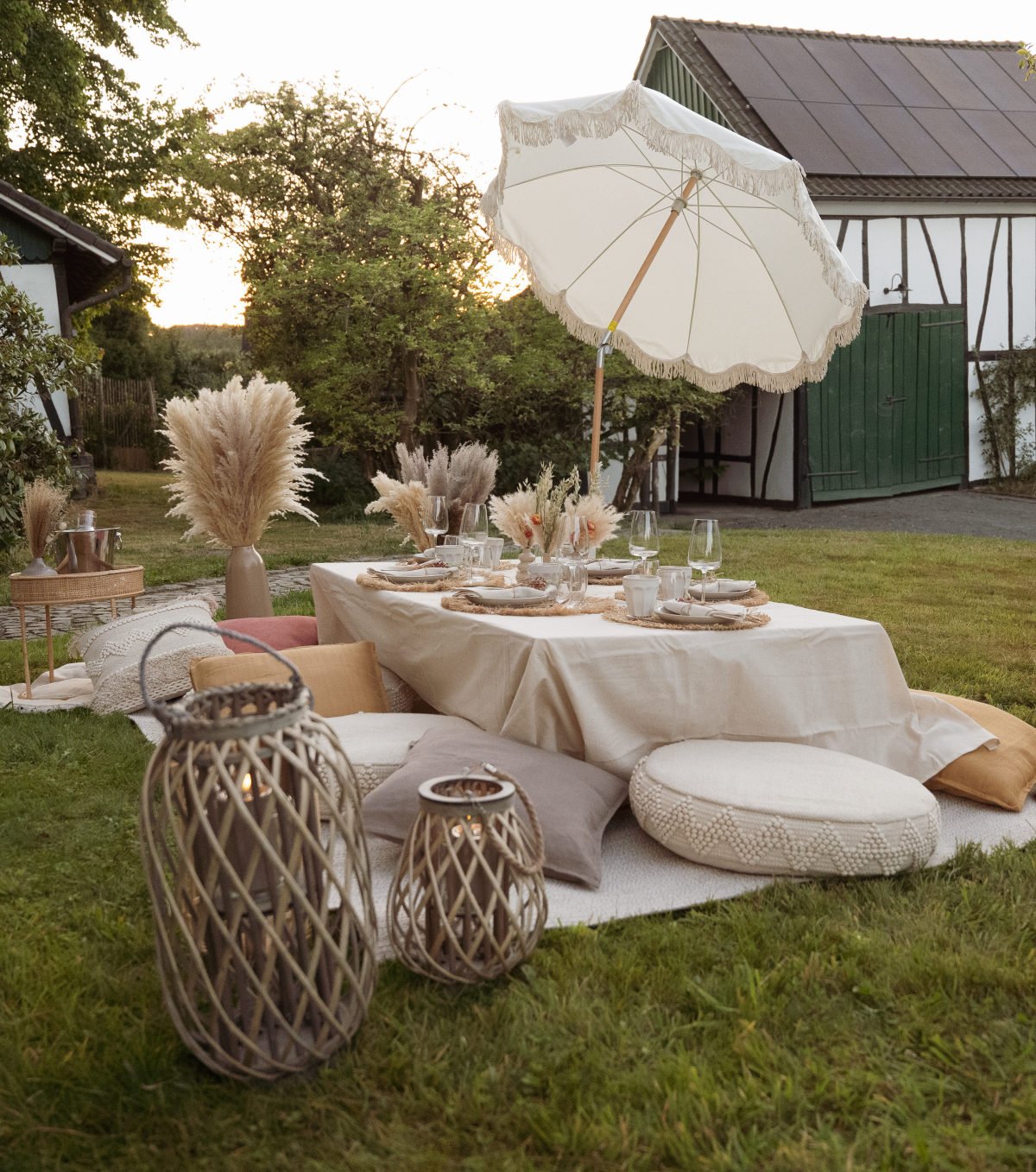 Aufgebautes Boho-Picknick mit Sonnenschirm, Kissen und Dekoration